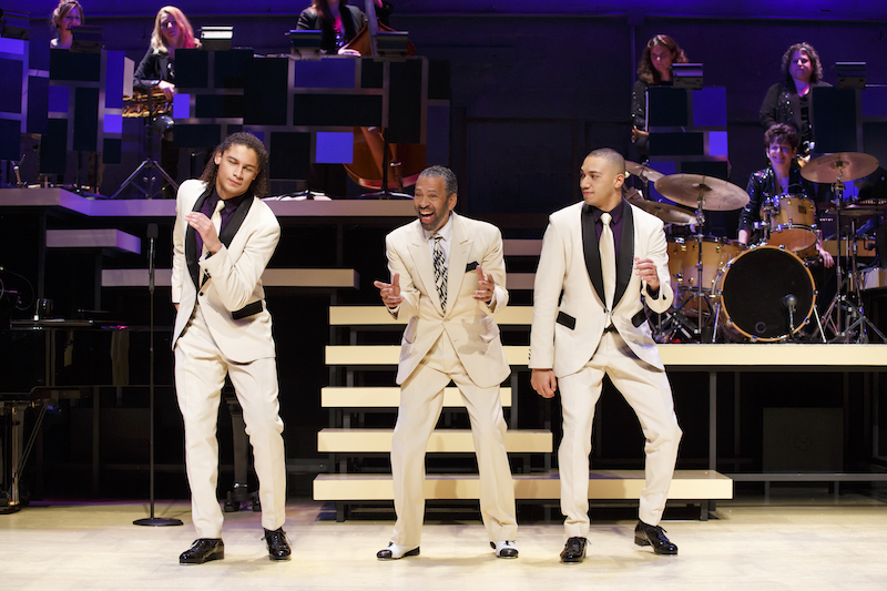 Maurice Hines, with brother tappers the Manzaris, dance together onstage with musicians in the background